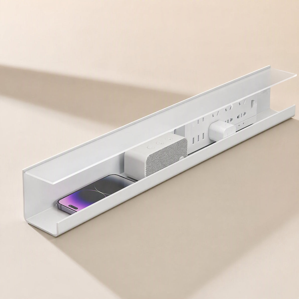 Wireledge – White cable tray seen from the end, holding a phone, speaker, power strip and charger inside