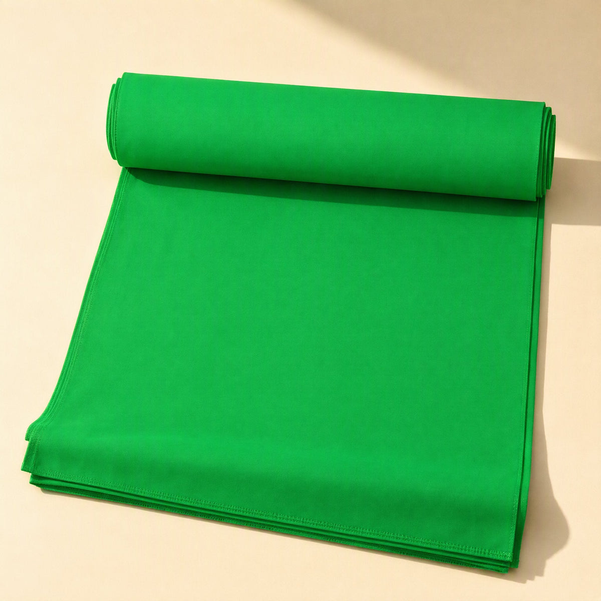 Screenweave – Green background cloth partly unrolled on a flat surface, showing the stitched edge and rolled top