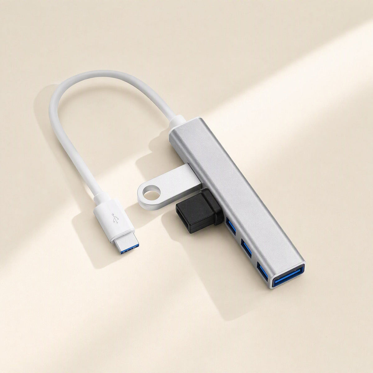 Metalbay – Silver four-port USB hub with white USB-C cable, a flash drive and a black plug inserted in side ports