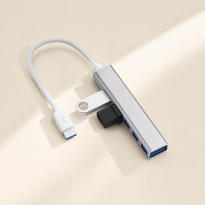 Metalbay – Silver four-port USB hub with white USB-C cable, a flash drive and a black plug inserted in side ports