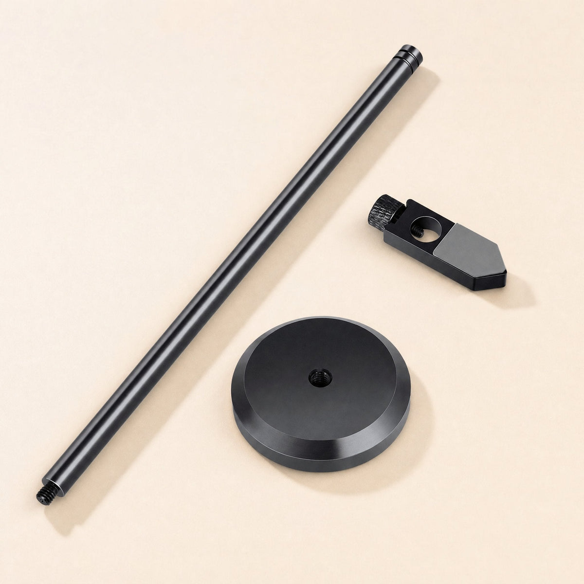 Stronghold – Disassembled black bracket parts: threaded pole, round base and clamp arm with thumbscrew, on beige