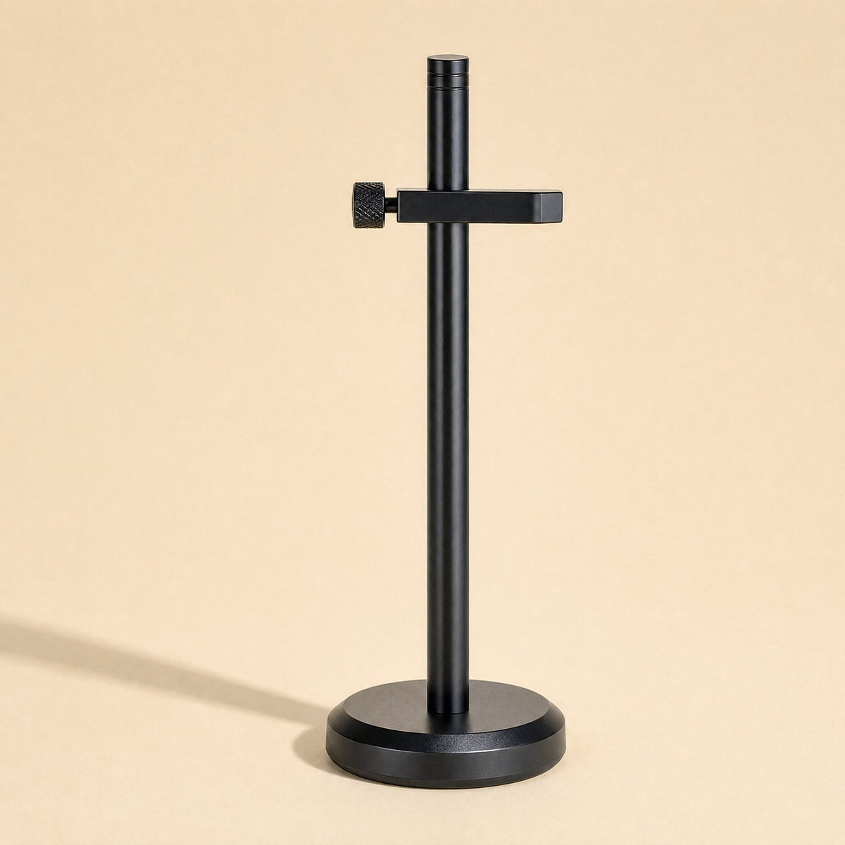 Stronghold – Black bracket with a single clamp arm and thumbscrew on a round weighted base, with a soft shadow
