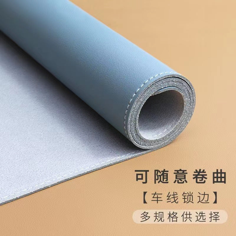 Hideloft – Blue leather desk mat rolled at one end, showing grey felt backing and stitched edge, on a tan surface