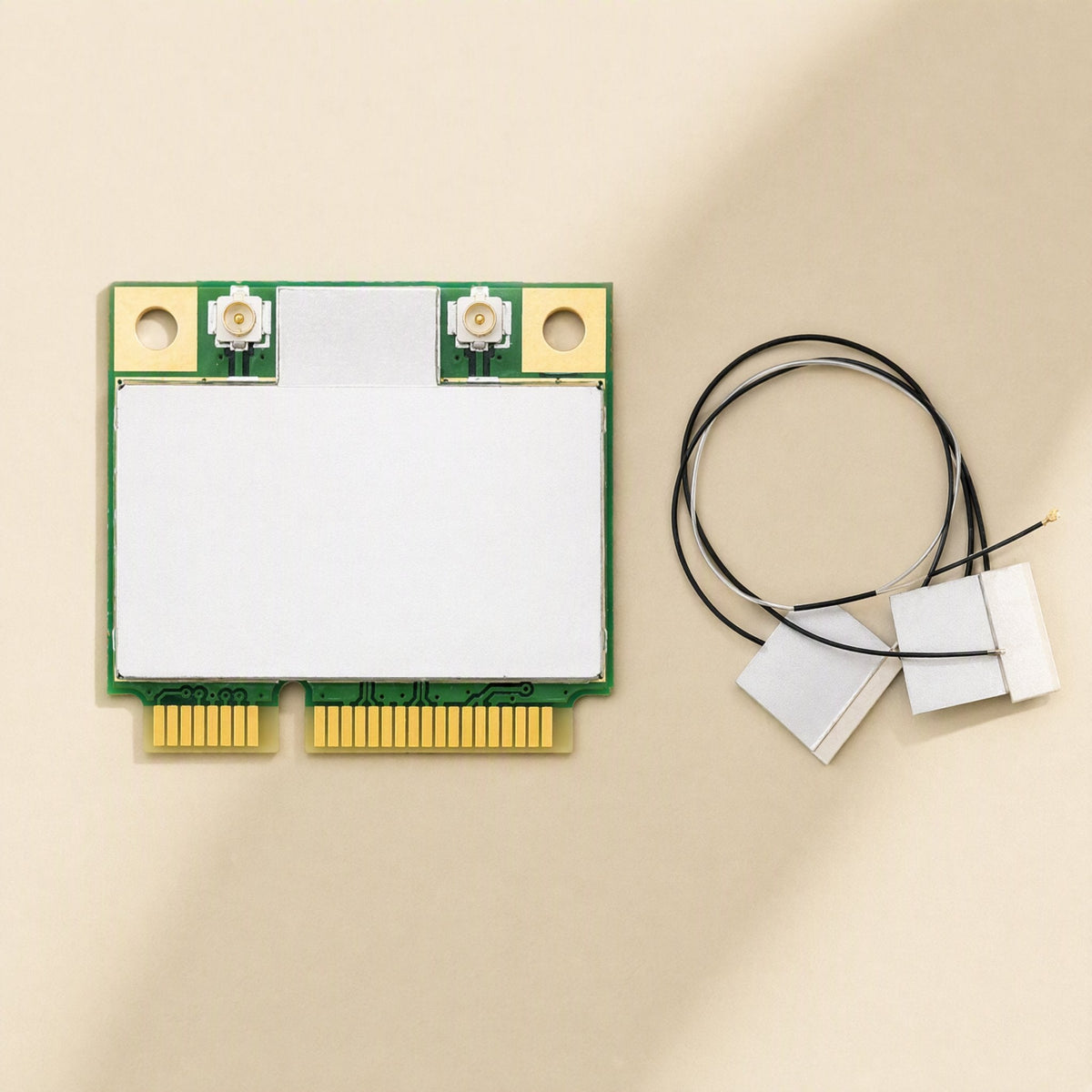 Linkchip – Mini PCIe card beside two flat internal antennas with thin black and white cables, top-down view