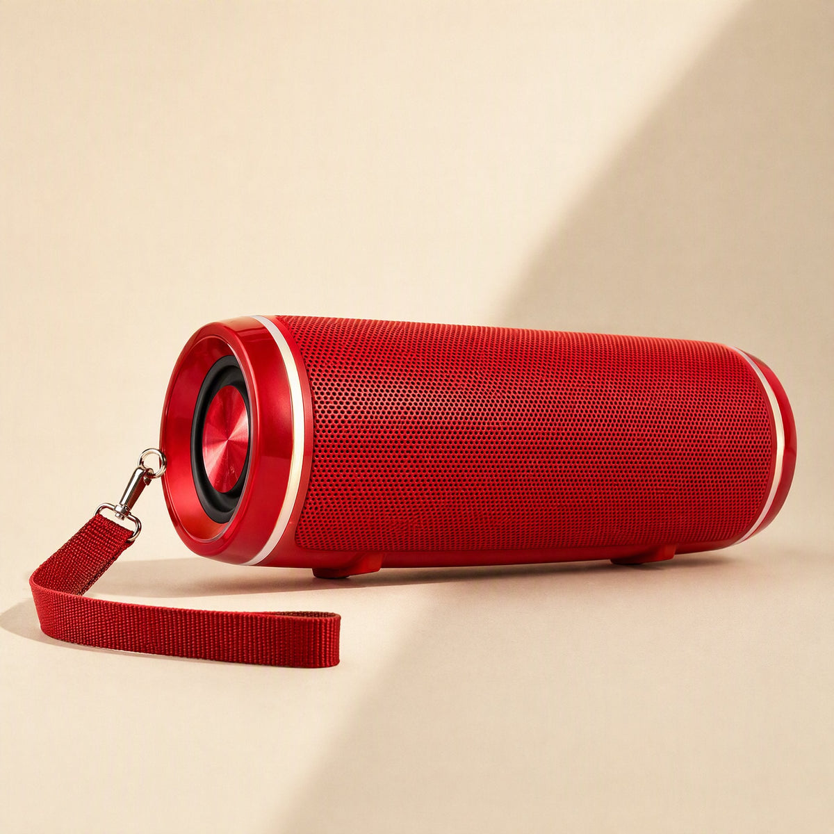 Strapsonic Bluetooth Speaker in red with a woven fabric wrist strap, lying on a beige surface