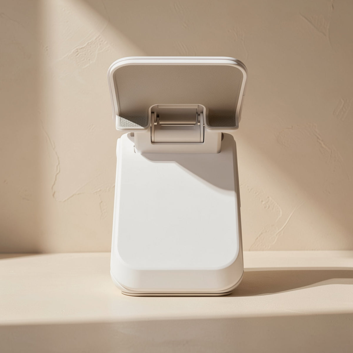 Tiltfold – Back view of a white folding phone stand with a silver hinge and angled cradle in soft shadow