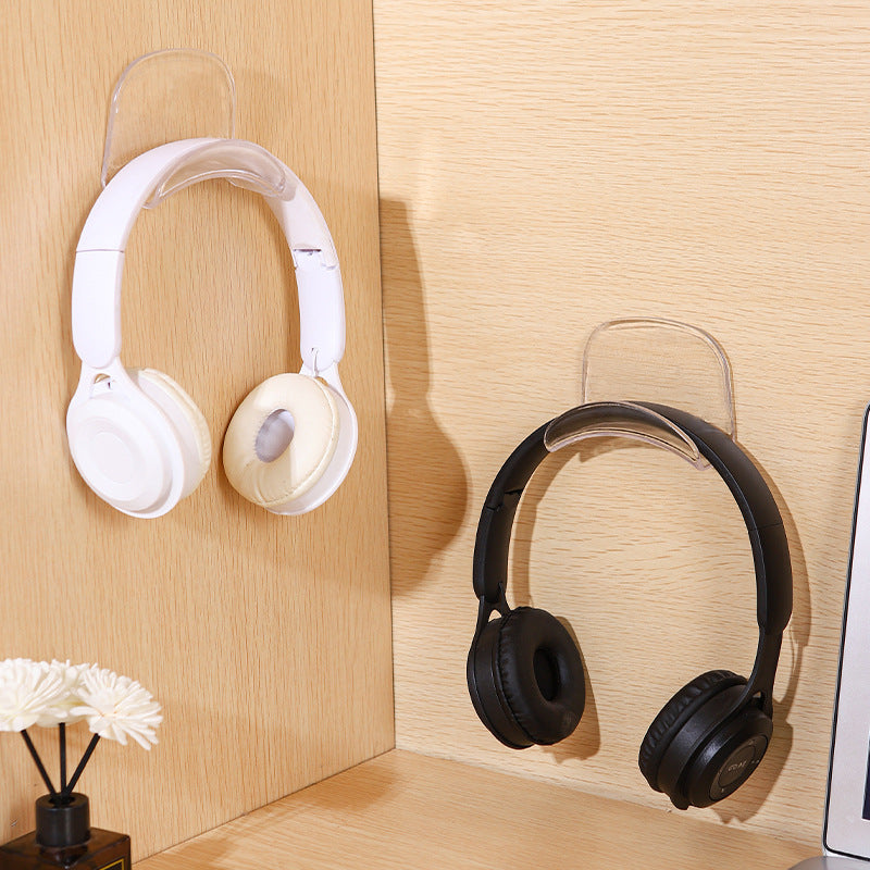 Hooksound No-Drill Bluetooth Headset Wall Hook in clear, holding white and black headphones on a wood wall