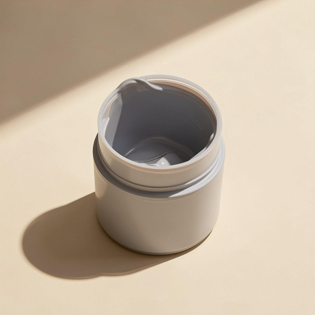 Pasteflow – Open gray jar seen from above, showing a smear of paste inside the rim