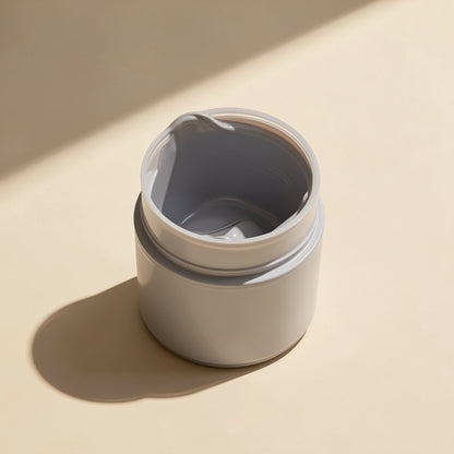 Pasteflow – Open gray jar seen from above, showing a smear of paste inside the rim