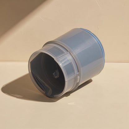 Pasteflow – Translucent gray jar tilted on its side with the opening facing the camera, blue lid edge visible