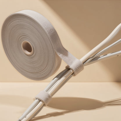 Wrapcord – Roll of hook-and-loop tape with two strips fastened around a bundle of white cables, in sunlight