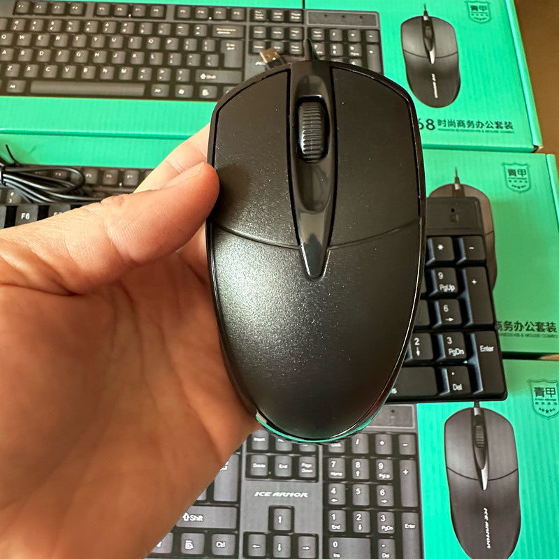 Clicktide – Hand holding a black two-button mouse with scroll wheel, keyboard and boxes in the background
