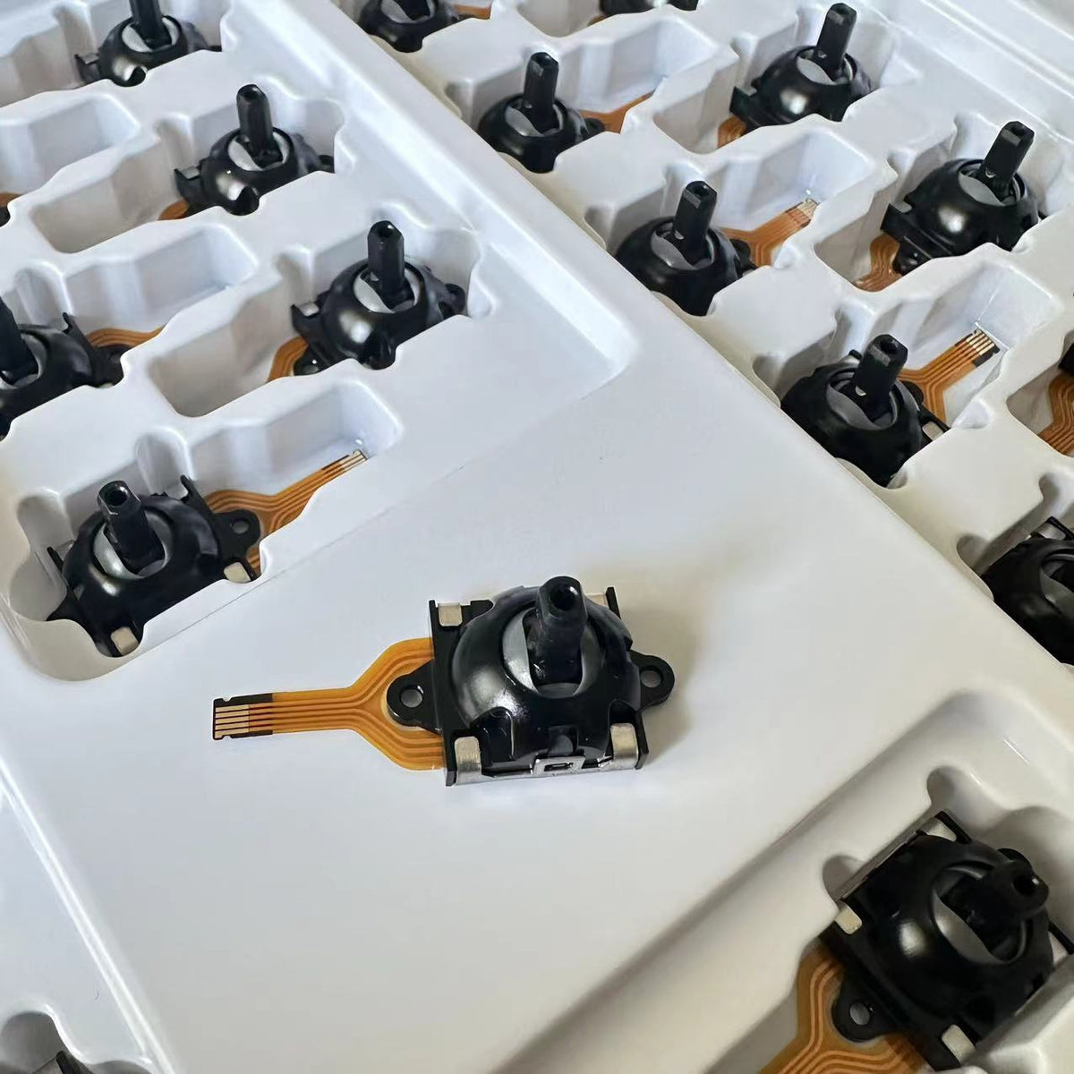 Driftfree Rog Ally Hall Joystick Replacement on a white tray with rows of black joysticks behind it