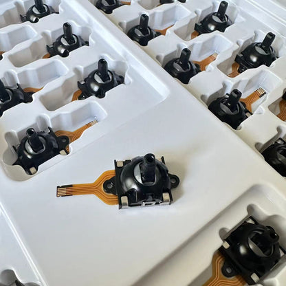 Driftfree Rog Ally Hall Joystick Replacement on a white tray with rows of black joysticks behind it