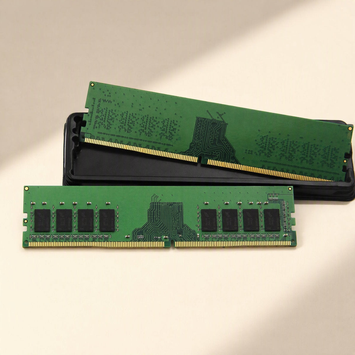 Byteboost – One green memory module resting on a black tray beside another module lying flat, gold contacts visible