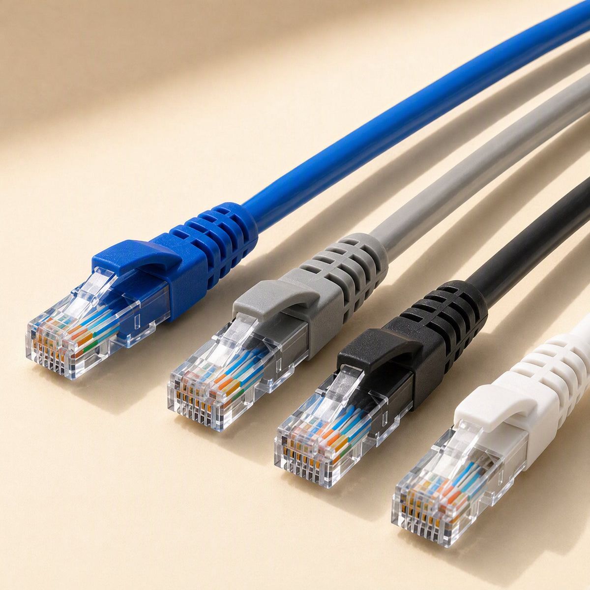 Fastlink – Row of blue, grey, black and white RJ45 patch cables with clear connectors on a cream surface