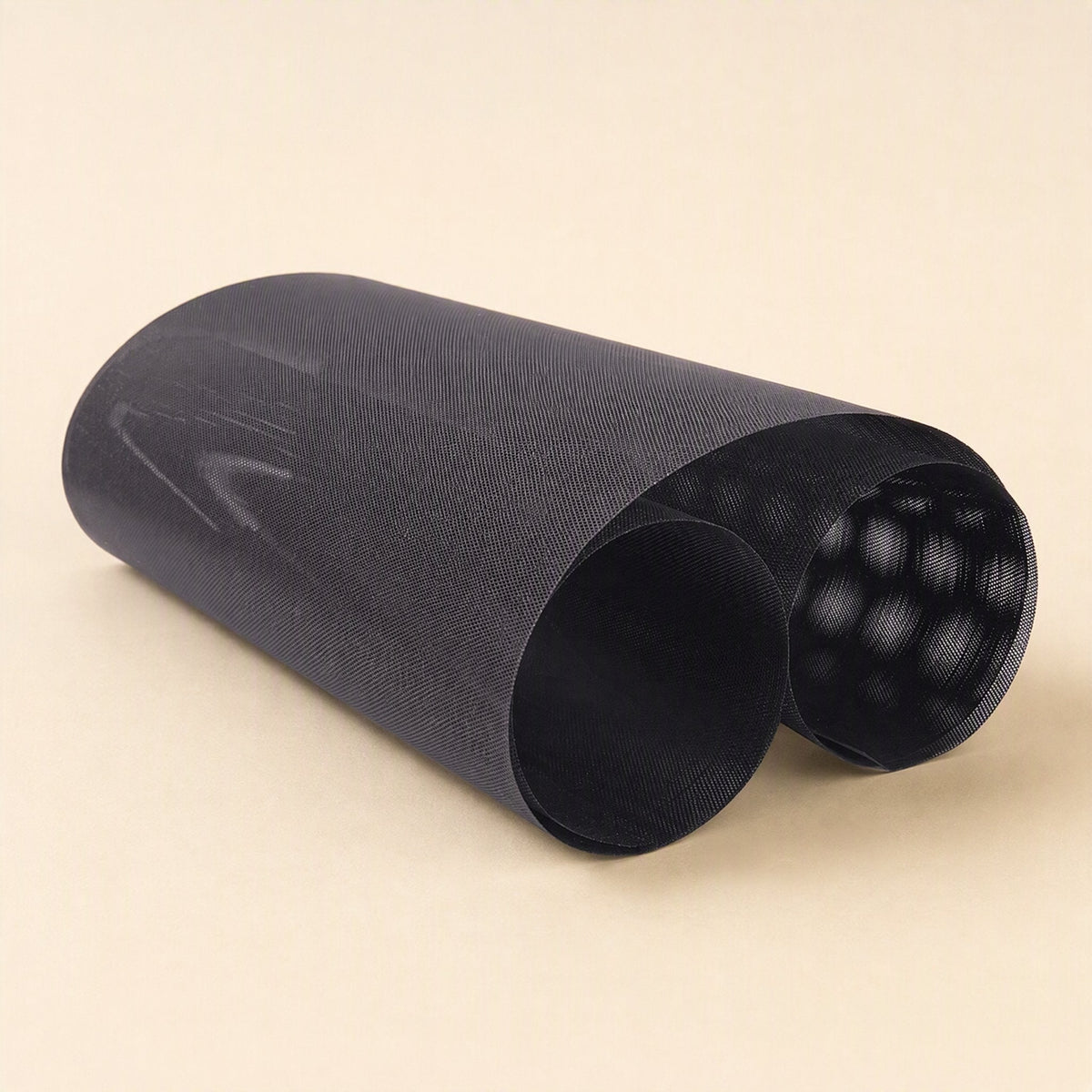 Netshield PVC computer case dust filter net, black mesh sheet loosely rolled on a cream background