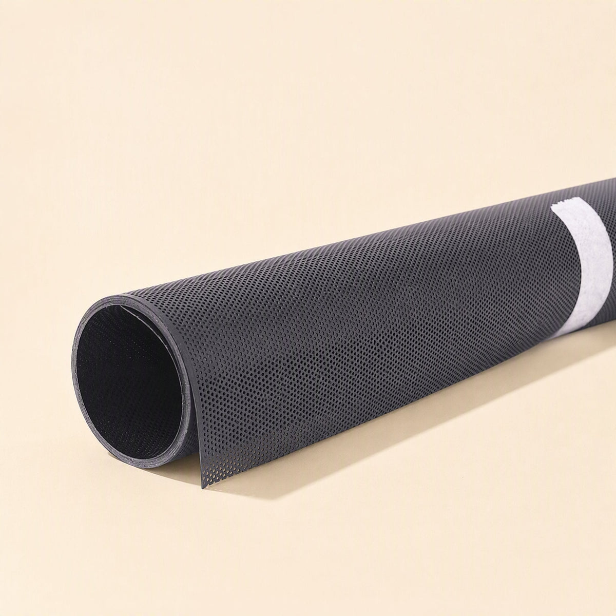 Netshield – Close-up of a rolled black perforated mesh sheet with a white adhesive strip along its edge