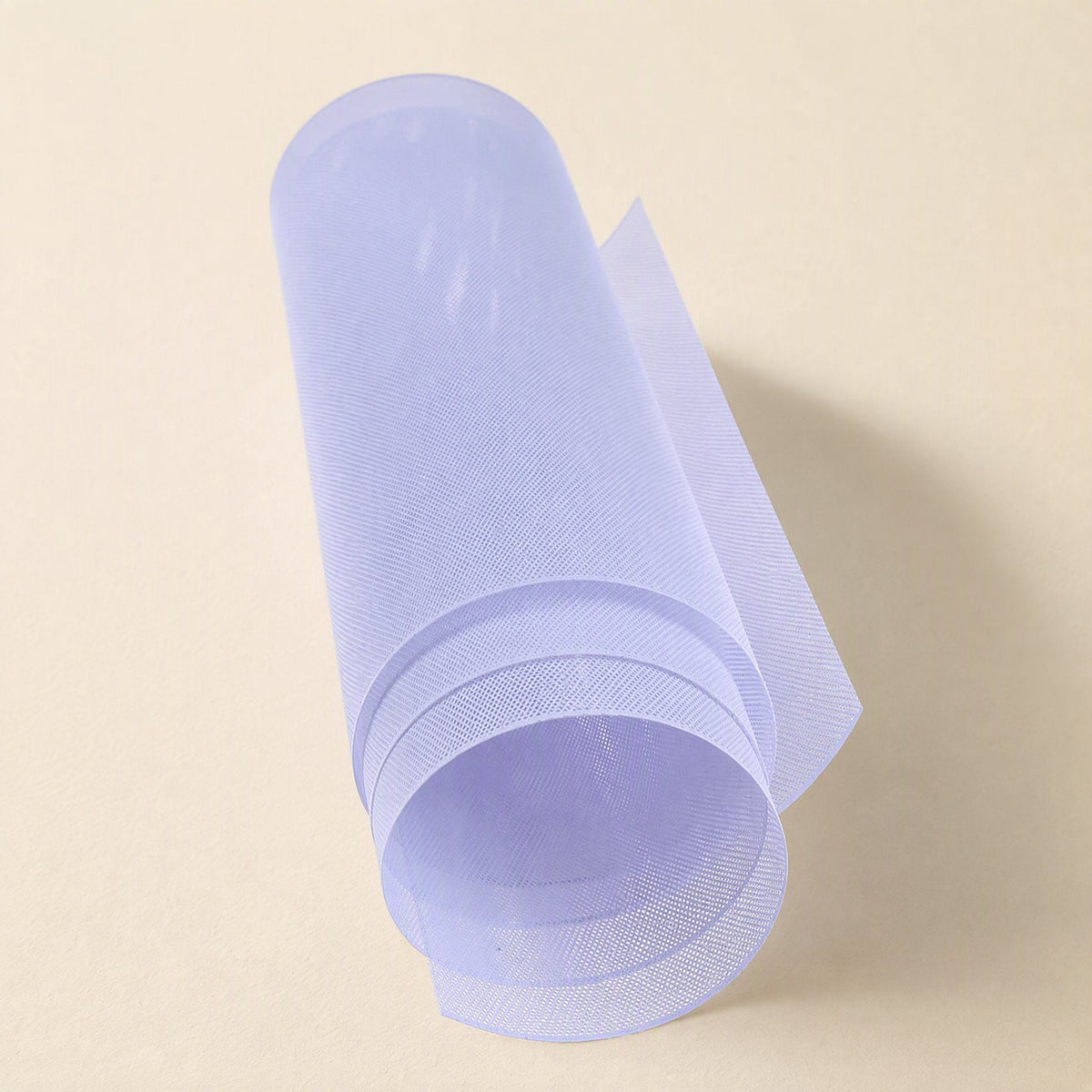 Netshield – Translucent pale lavender mesh sheet curled into a loose roll against a cream backdrop