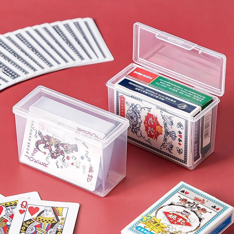 Flipdeck plastic card storage box with flip cover, two clear boxes holding playing cards on a red table