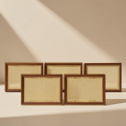 Aluperch – Five wooden picture frames with brown borders and cream mats arranged in two rows against a beige wall
