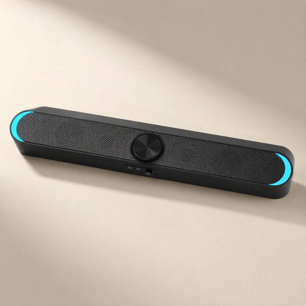 Desksonic – Black mesh-front speaker with cyan glowing ends and a round center knob, shown from a low angle