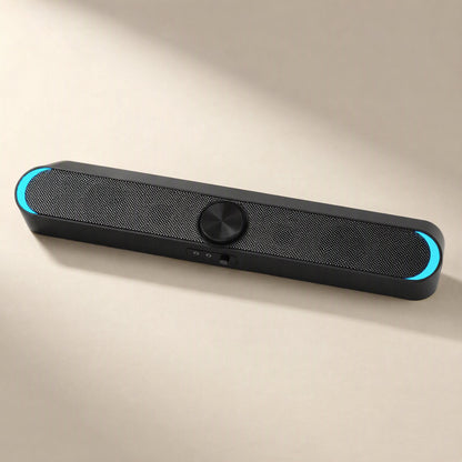 Desksonic – Black mesh-front speaker with cyan glowing ends and a round center knob, shown from a low angle