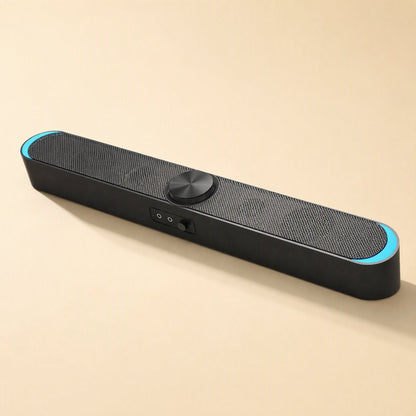 Desksonic – Front-angled view of the black speaker with light blue end glow, center dial and two jacks beside a switch