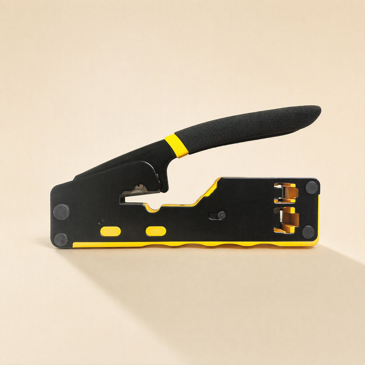Cablepress – Flat side view of the crimping pliers casting a soft shadow, with the gold-toned crimp dies visible at the right
