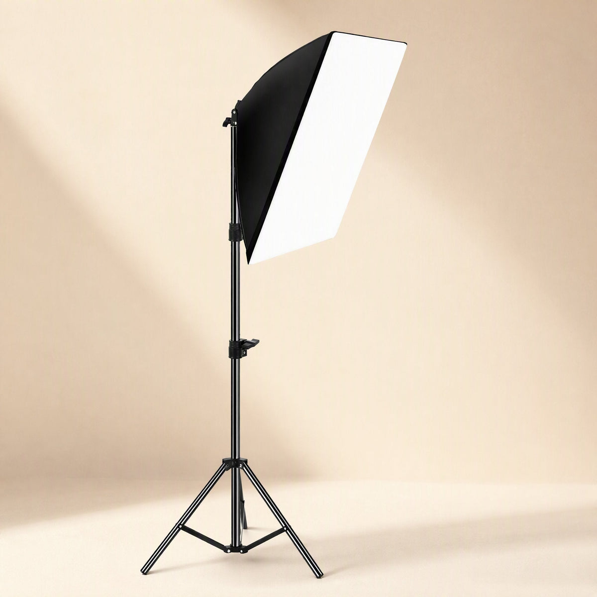 Faceglow – Single softbox light on a black tripod stand, angled down, in a warm beige studio setting