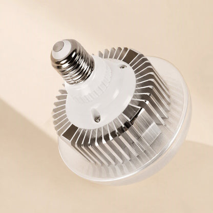 Faceglow – Close-up of an E27 LED bulb with silver heat-sink fins, white base and clear ribbed lens on a beige background
