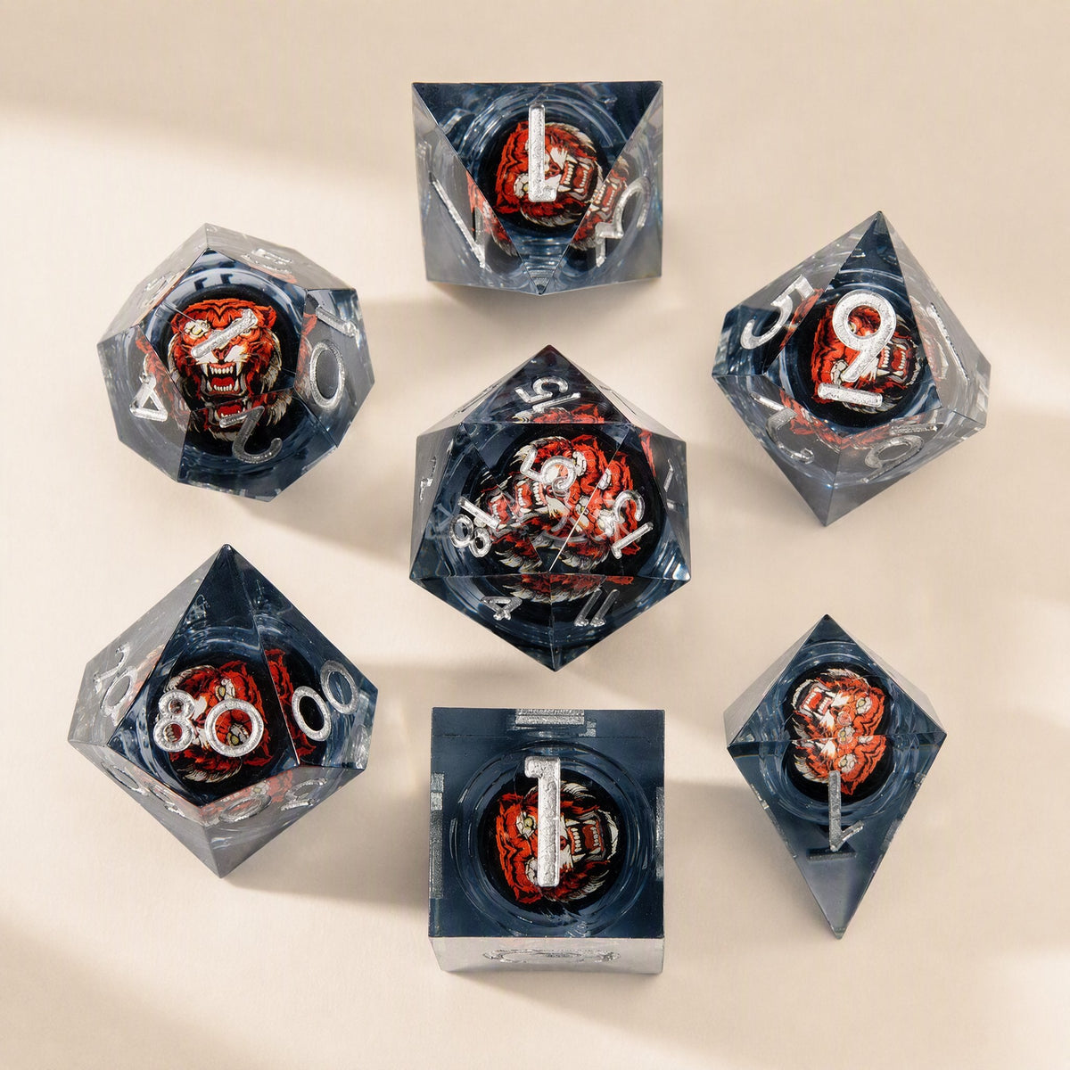Fateforge – Grey resin dice with silver numerals and a red-orange tiger face inside each die, laid out on a cream surface