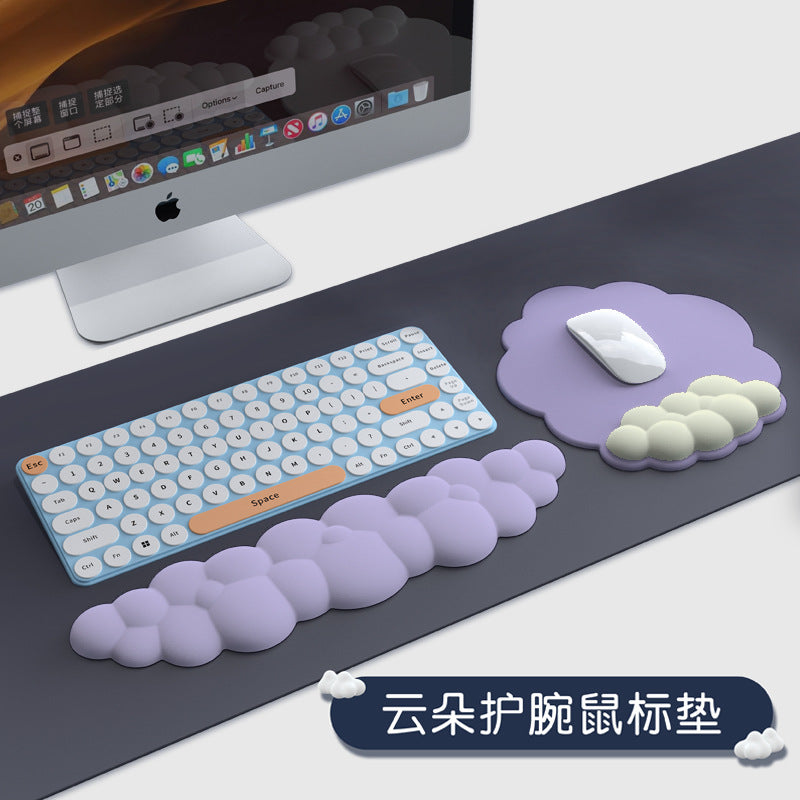 Wristnest rubber mouse pad with wrist rest in lavender cloud shapes beside a blue keyboard and iMac on a desk