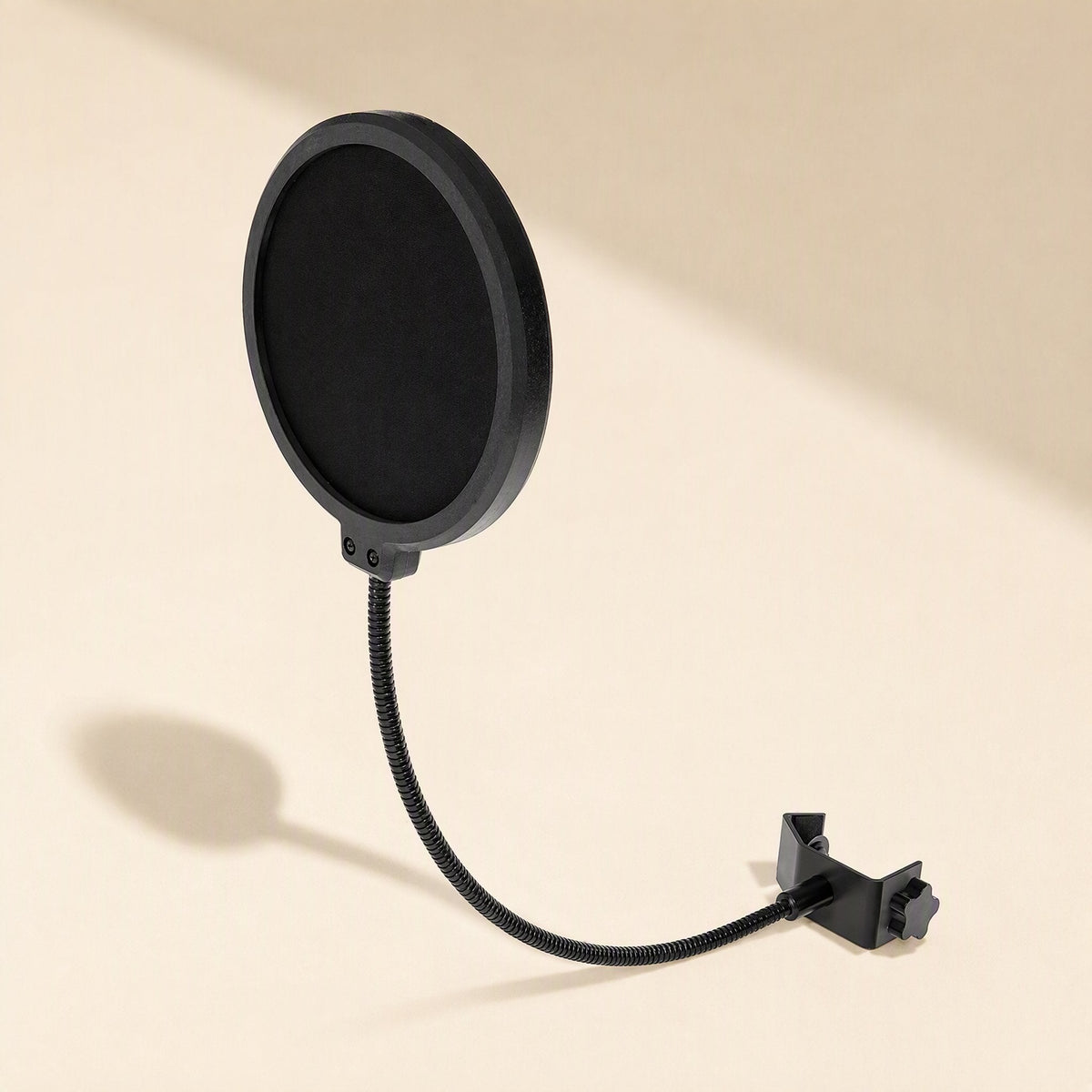 Meshhush – Angled view of the black mesh pop filter with curved gooseneck and clamp, casting a shadow on a cream backdrop