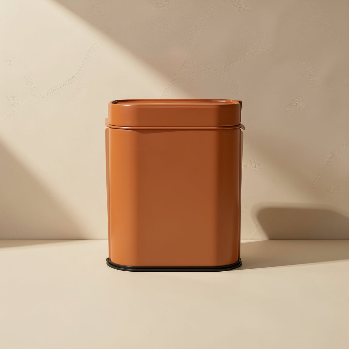Typeport – Terracotta-orange rectangular container with a black base against a cream wall in soft light