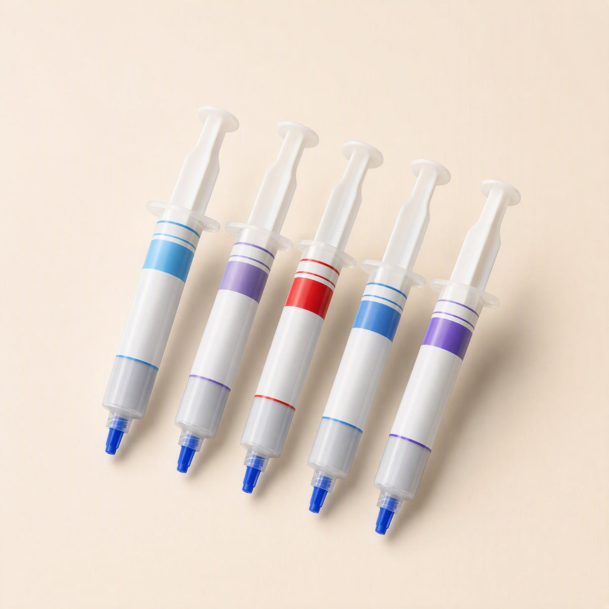 Silkspread CPU Thermal Paste syringes in five colour-banded versions, laid out in a row on a cream background