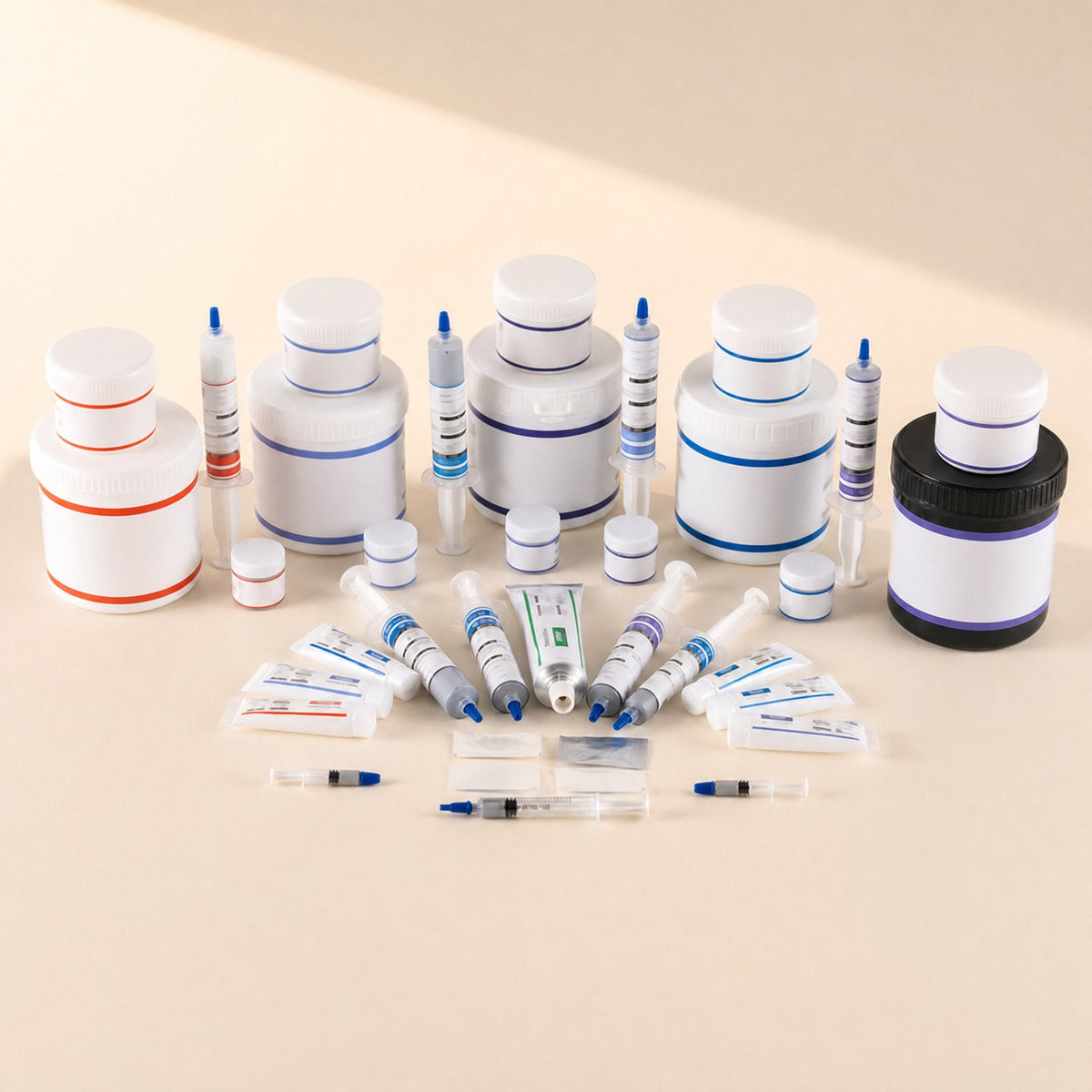Silkspread – Assorted thermal grease jars, syringes, tubes and sample sachets arranged in a group on a beige background