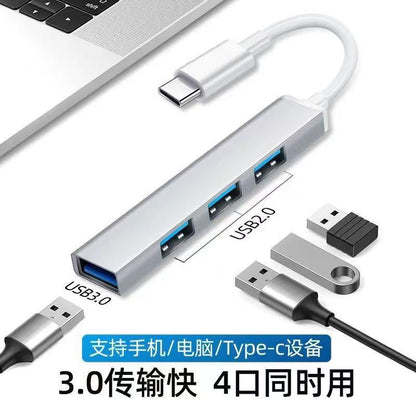 Alloyhub – Silver four-port hub with Type-C cable beside a laptop, with USB 3.0 and USB 2.0 ports marked, plugs nearby