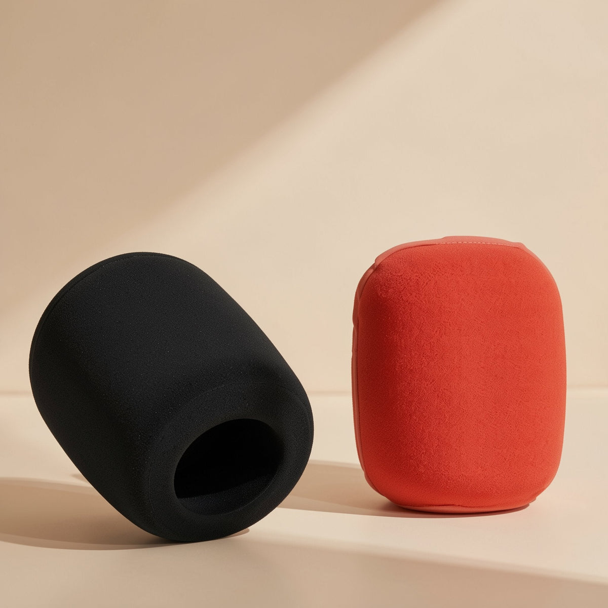 Micmuffle Sponge Microphone Cover in black and red, side by side on a cream surface with hollow opening visible