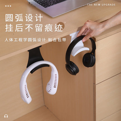 Perchloop – Hand hanging black headphones on a white holder under a desk, beside a black holder with a neck fan