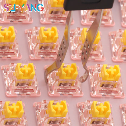 Pryloop – Wire tips of the keycap puller gripping a yellow switch on a pink keyboard switch board