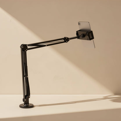 Clampmate – Black cantilever arm with round weighted base holding a tablet at an angle, side view in warm light