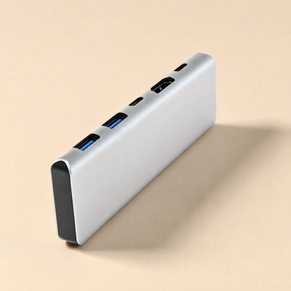 Portpocket – Slim silver docking station standing on its edge, showing two blue USB-A ports, USB-C slot and HDMI port