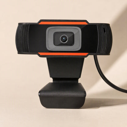 Voicelens – Front view of the black webcam with orange stripes, ribbed side grilles and USB cable trailing to the right