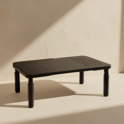 Screenlift Alloy Steel Monitor Computer Stand in black with ventilated top, lit by angled sunlight on a cream wall