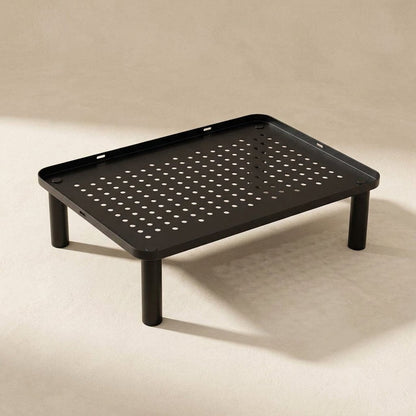 Screenlift – Overhead three-quarter view of the black stand's perforated metal top, raised rim and four round legs