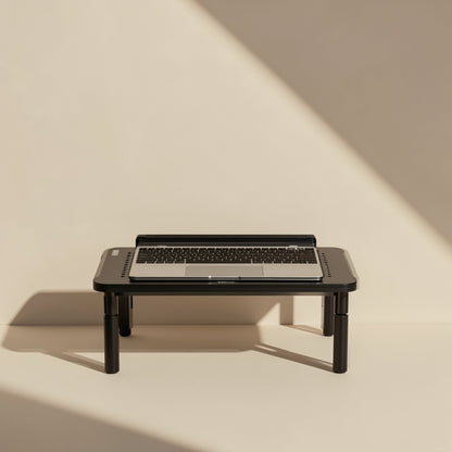 Screenlift – Laptop resting on the black stand, shown from the front with sunlight and shadow on a plain cream wall