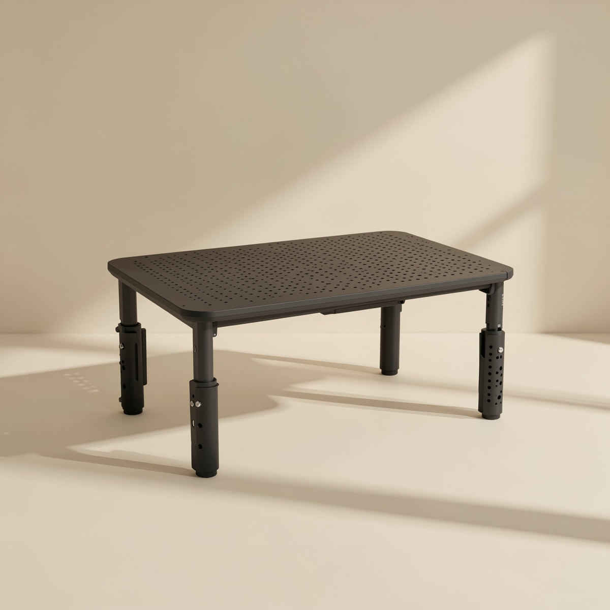 Screenlift – Black stand with uneven leg heights, showing the perforated tube legs and drilled adjustment holes up close
