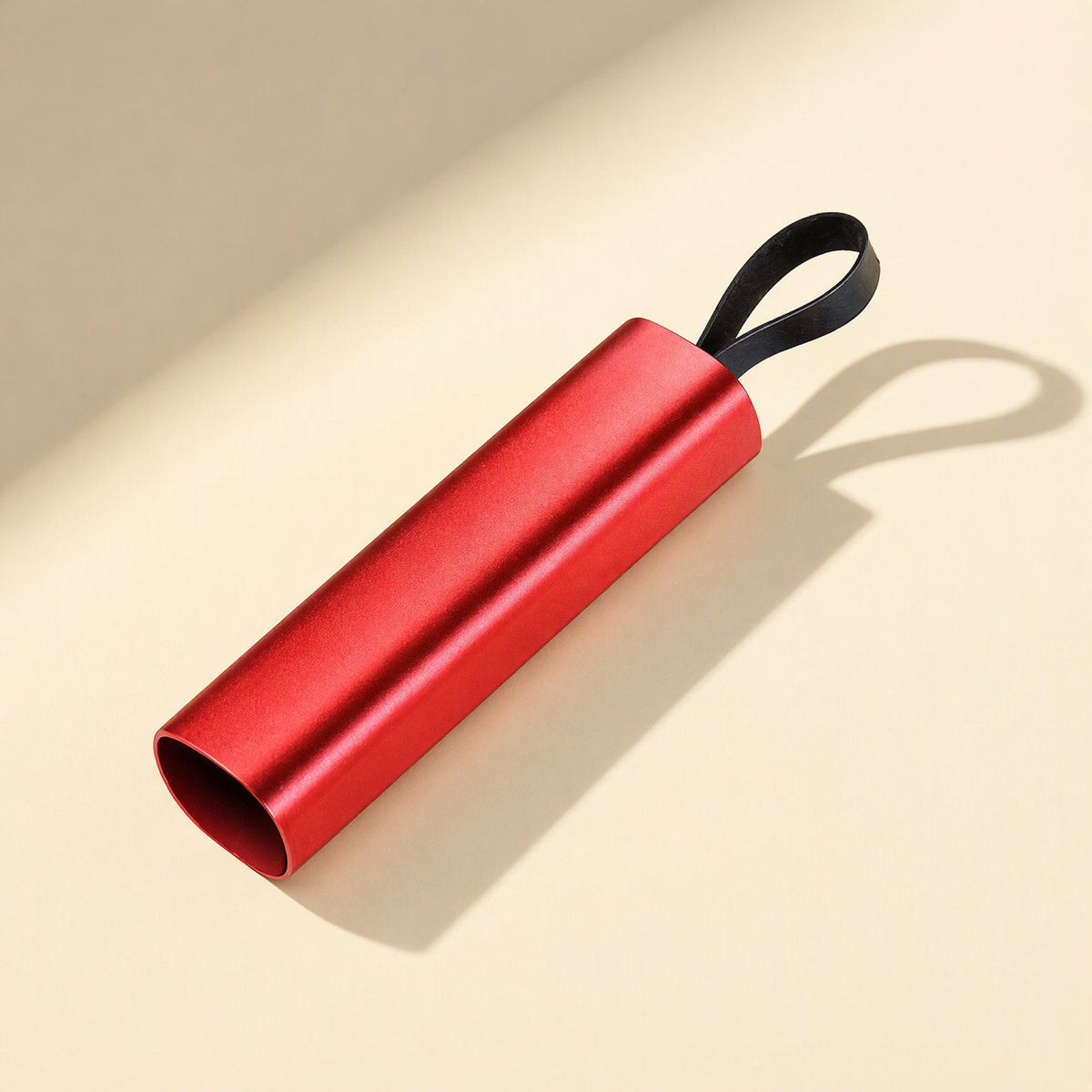 Quickcord Retractable Three-in-One Fast Charging Cable in red aluminum, open end angled on a cream surface