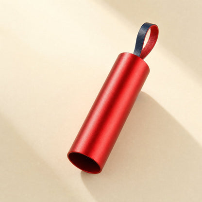 Quickcord – Red metal cylinder with a navy and red leather loop, open end facing the camera in soft light